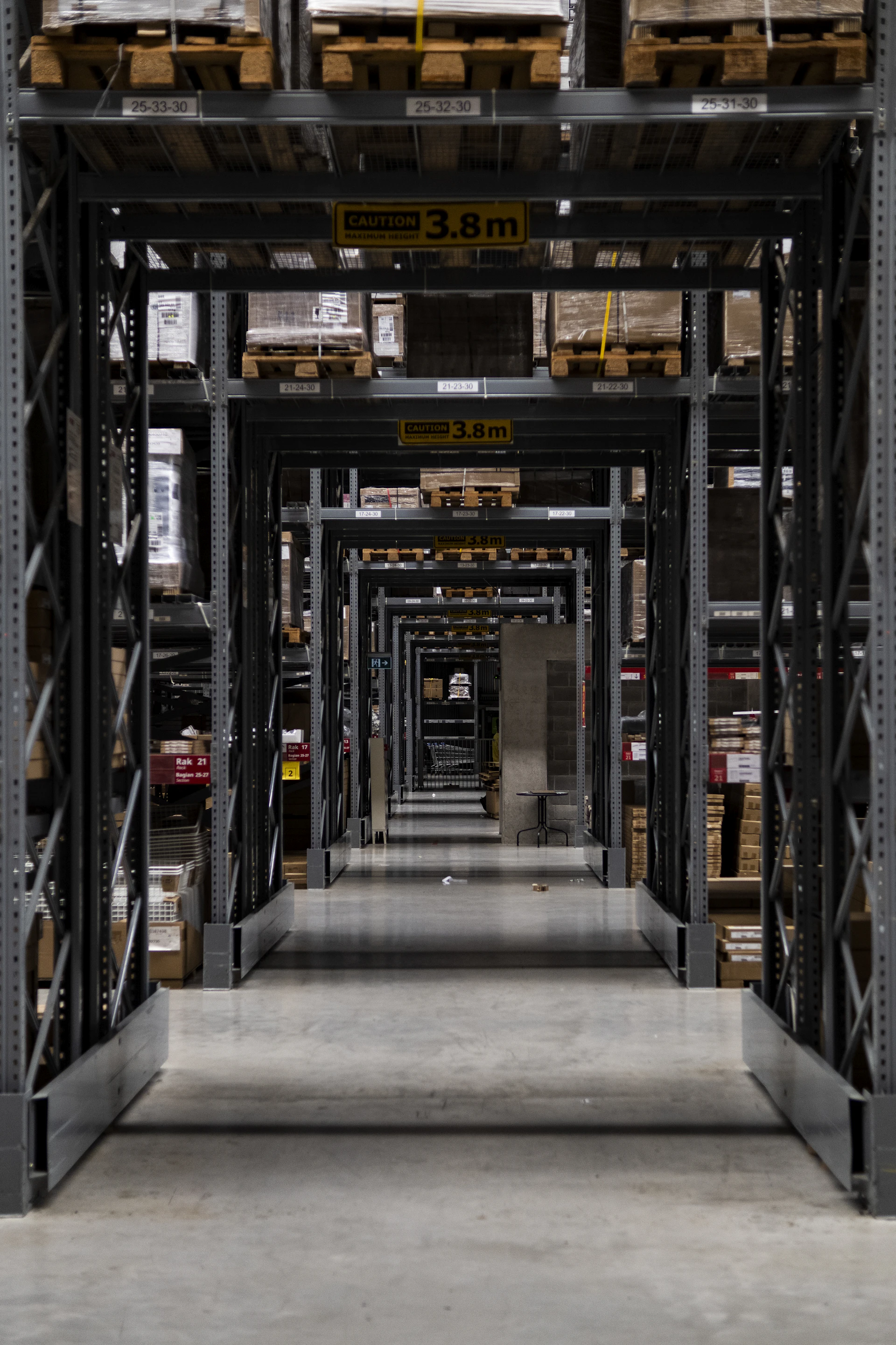 Interior view of a spacious, clean warehouse with neatly stacked pallets of pet food bags under soft industrial lighting.